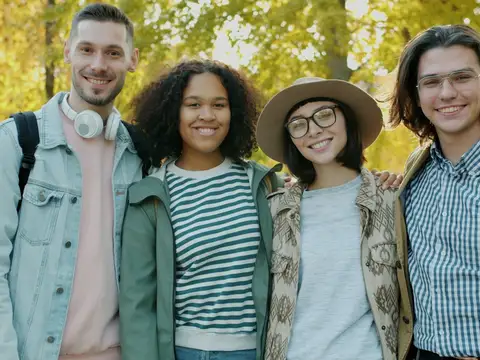 Vier junge Leute lächeln in einem Park im Herbst